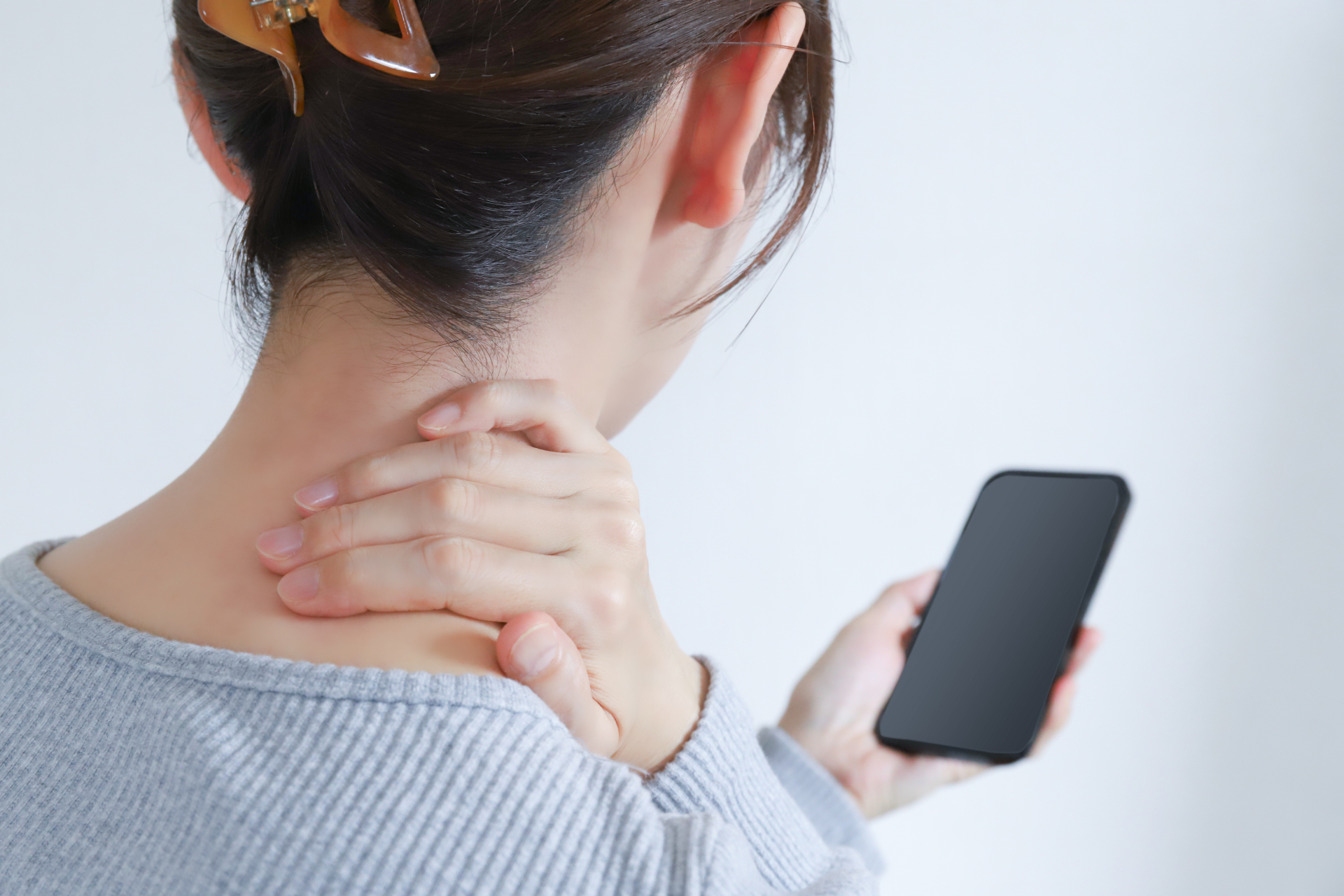 スマホ首で首の痛みを感じる女性（参考イメージ）