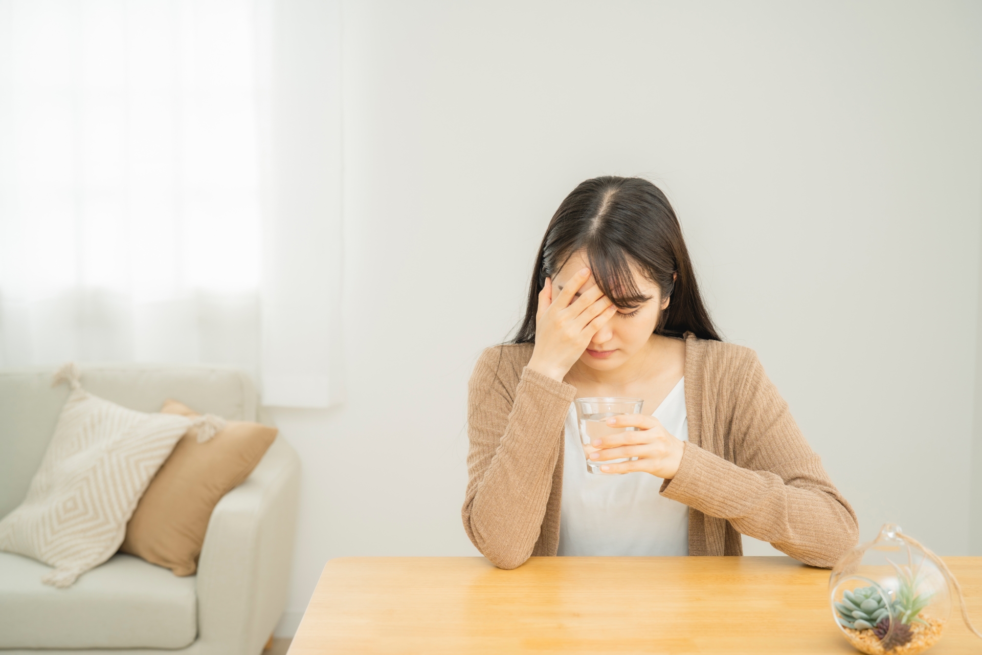 「体調不良の女性（頭痛）」頭痛・過労の一般イメージ。（参考イメージ）