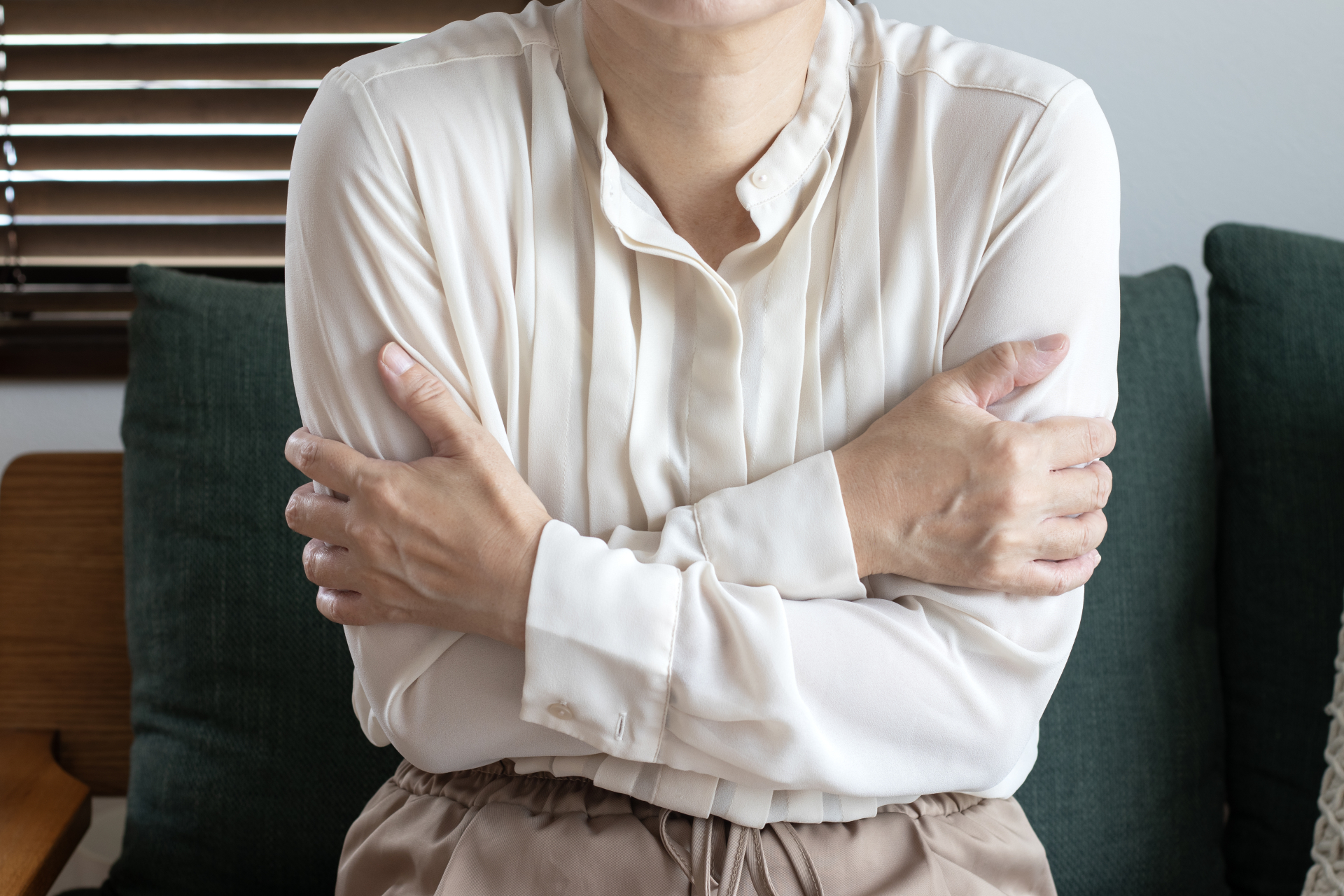 「寒くて身をすくめる女性」寒さを感じる人物。（参考イメージ）