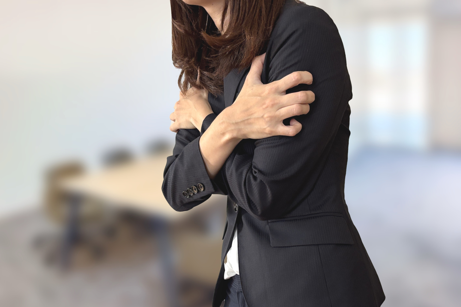 「オフィスの冷房が寒くて震えるビジネス女性」冷房環境による冷えのイメージ。（参考イメージ）