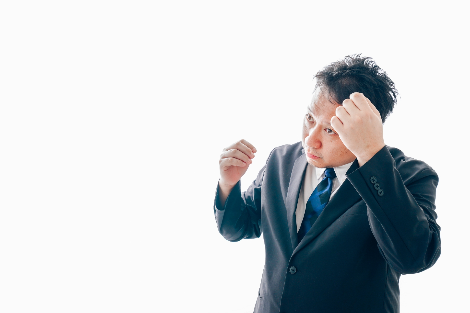 抜け毛に悩むスーツを着た中年男性（参考イメージ）