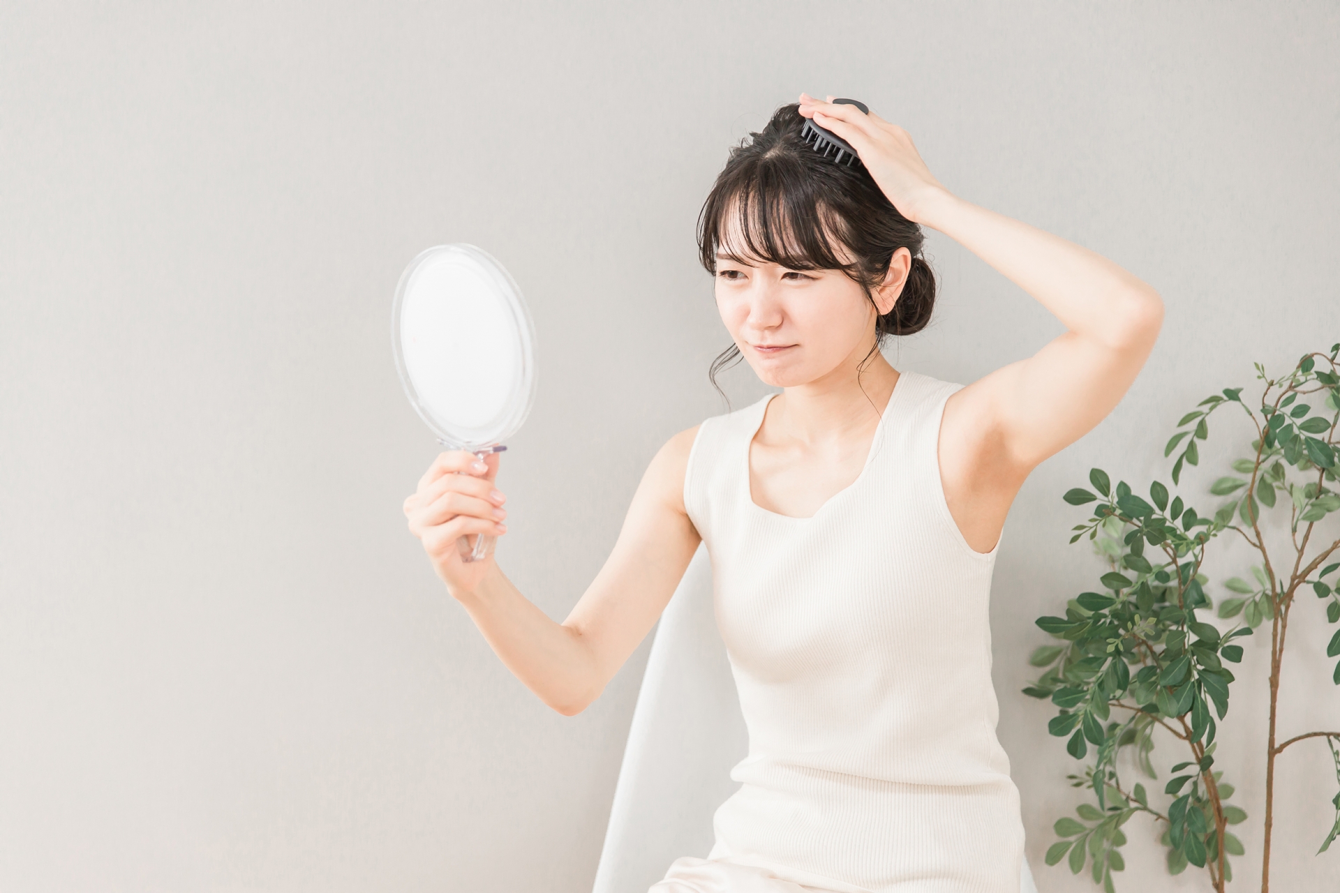 「鏡を見ながら頭皮マッサージをする困る女性」頭皮の悩み。（参考イメージ）